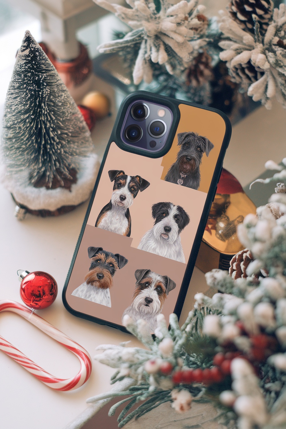 A phone case featuring illustrations of various terrier dog breeds, placed on a festive table with holiday decorations.