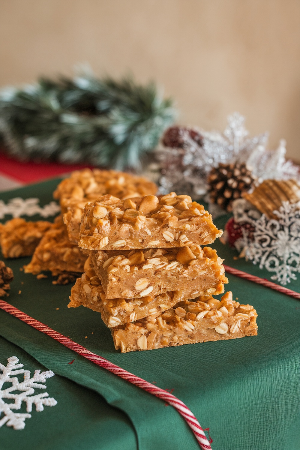 Homemade honey and oat dog bars stacked on a green surface with holiday decorations.