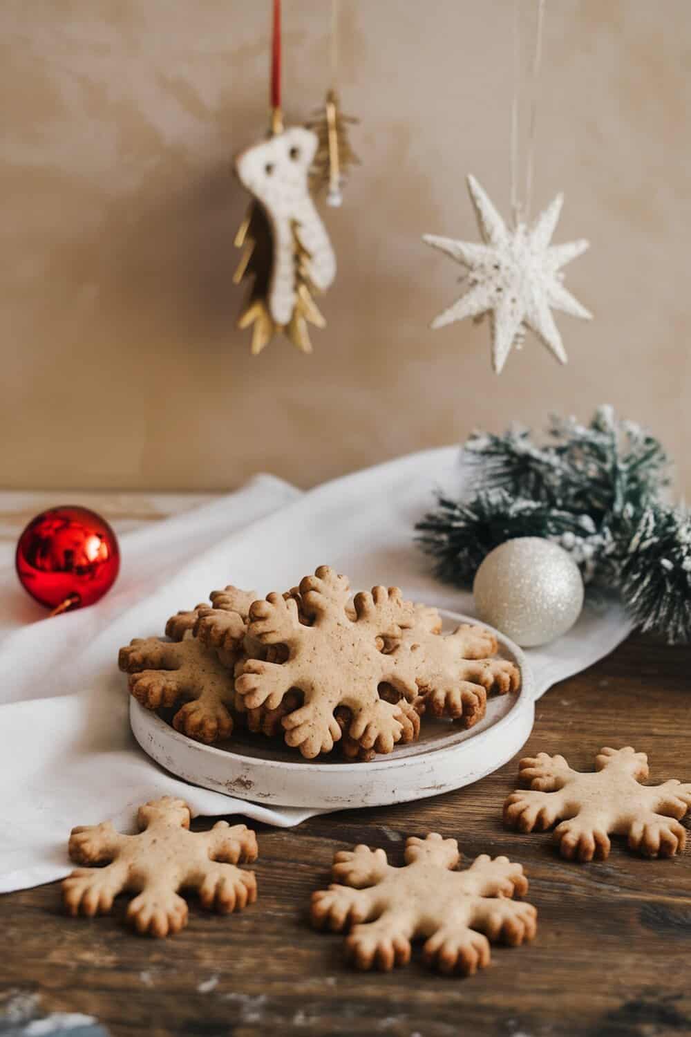A plate of snowflake-shaped cookies with festive decorations in the background.