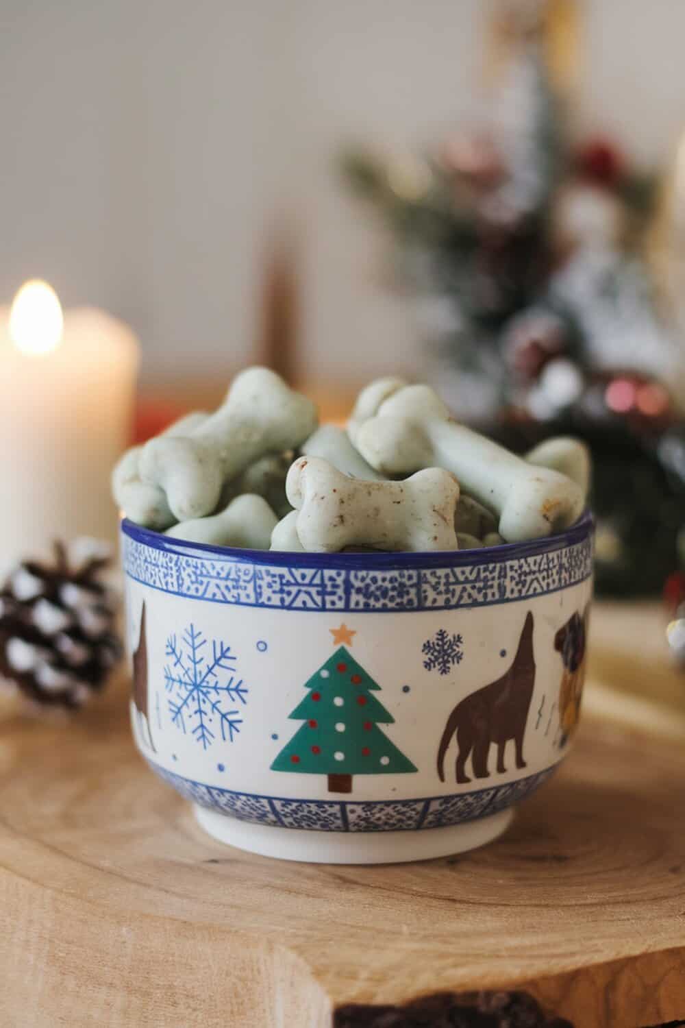 A bowl of minty dog treats shaped like bones, surrounded by festive decorations.