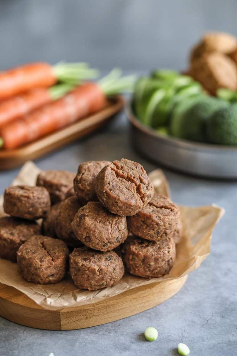 Stacked brown meat and veggie on a wooden cutting board with parchment paper. 
