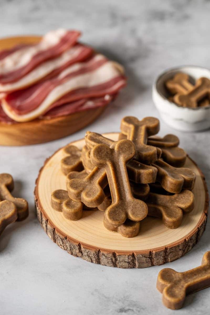 Dog treats on a rustic wooden slice with bark edges.