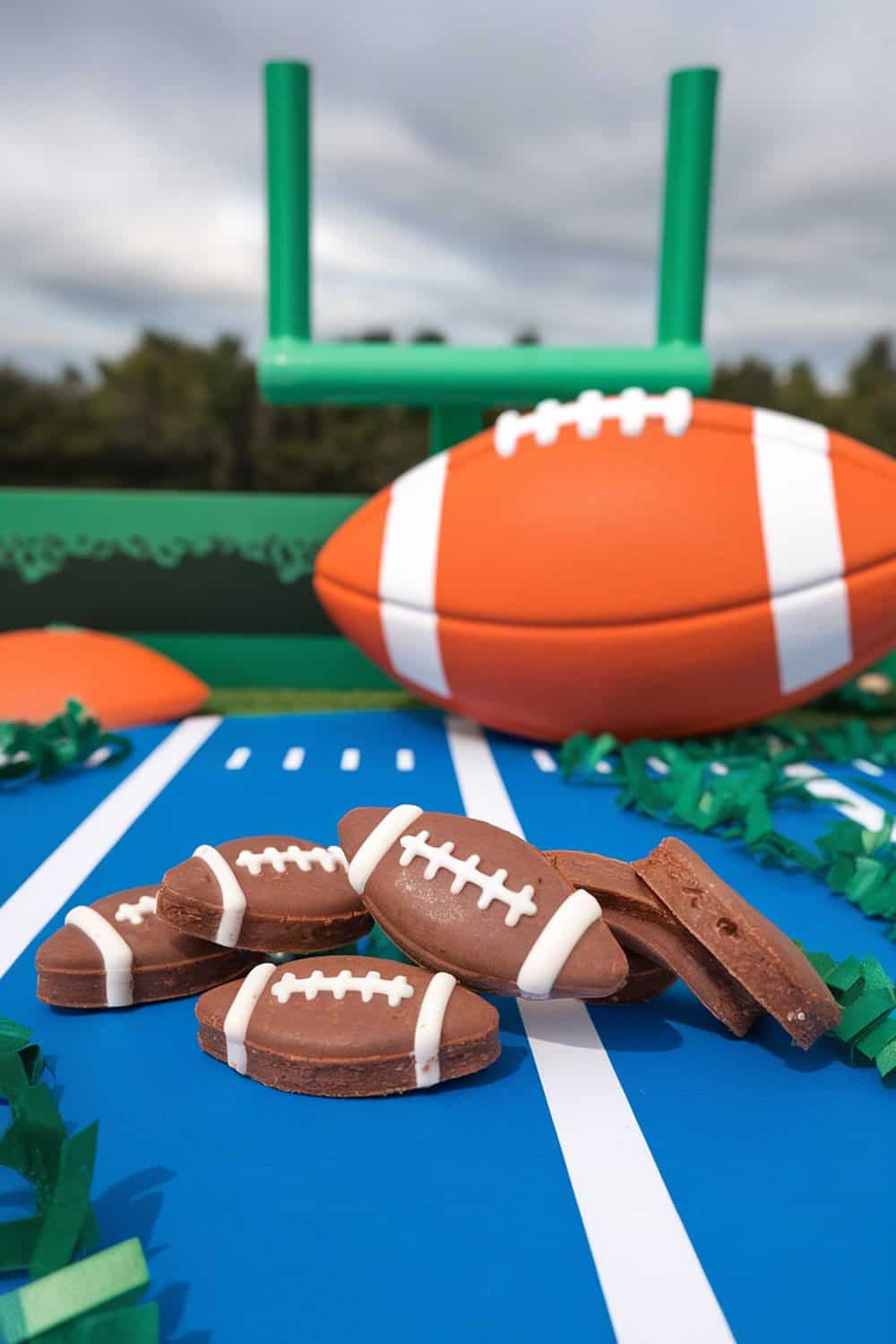 Beef liver dog treats shaped like footballs on a blue football field backdrop