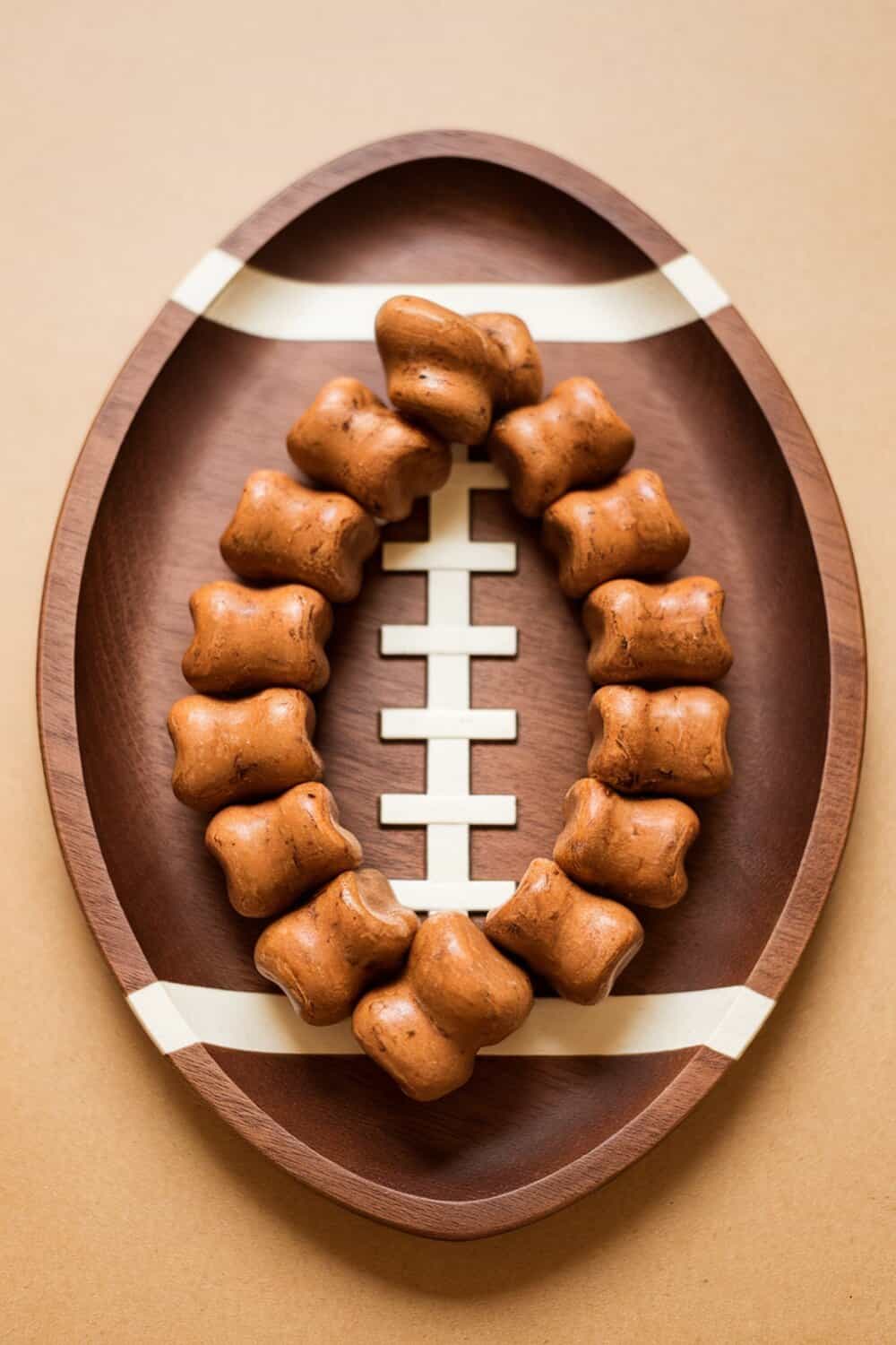 A wooden plate shaped like a football filled with dog treats.